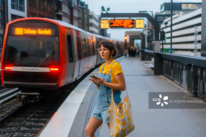 女人在地铁站等火车并使用智能手机图片素材