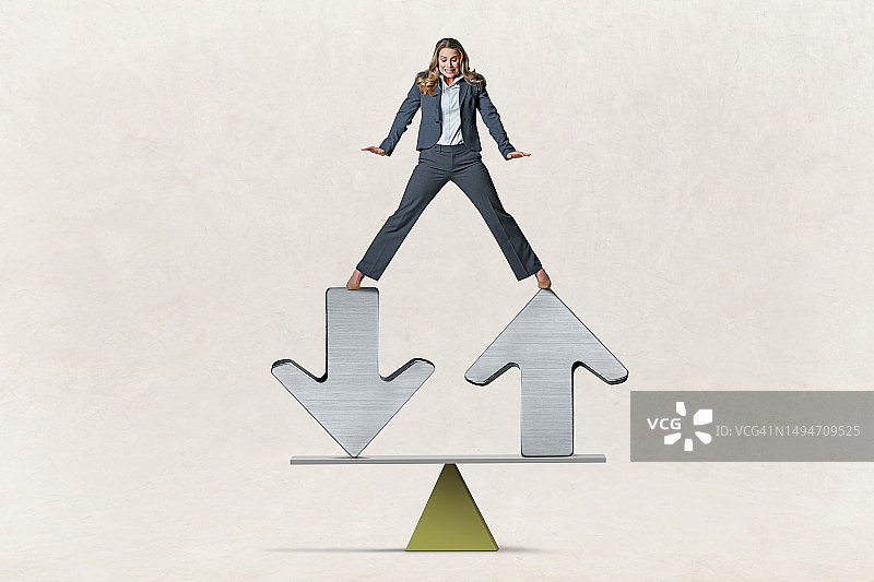 女人在跷跷板上的箭头上保持平衡图片素材
