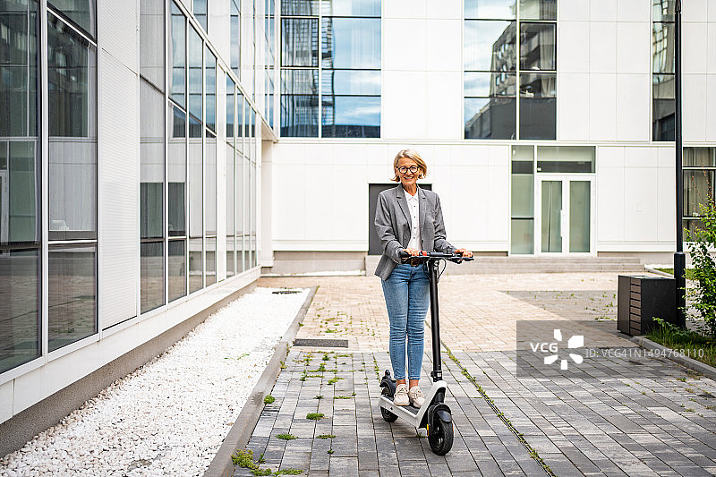 年长的女商人使用电动滑板车作为交通工具图片素材