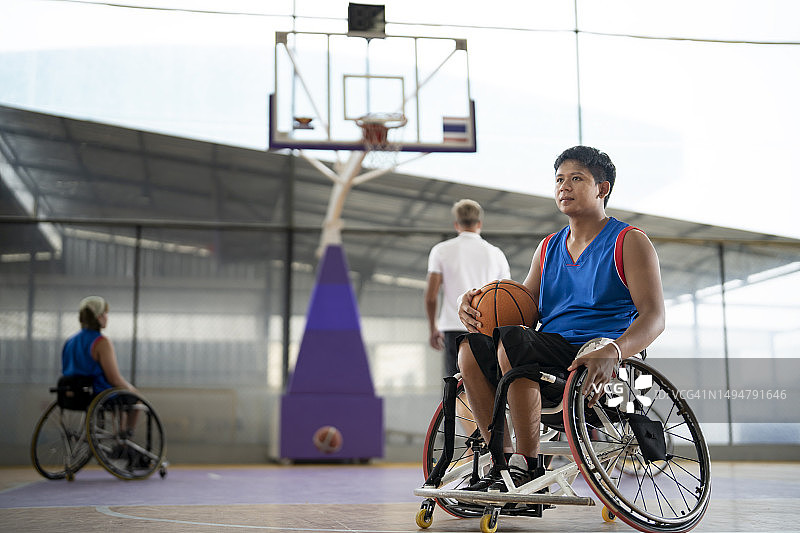 在体育馆训练中看着摄像头的轮椅篮球运动员图片素材