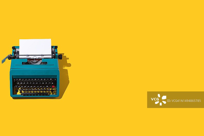 黄色背景上的绿色复古打字机和空白页图片素材