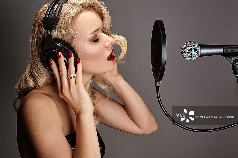金发女人在录音棚里用麦克风唱歌图片素材