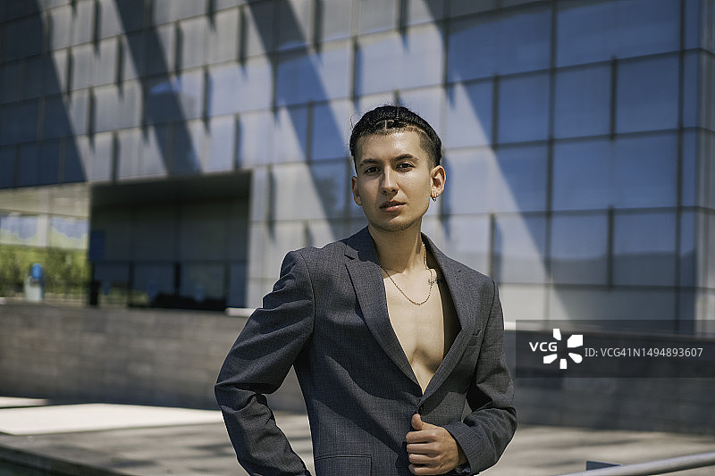 男孩梳着油头，在办公楼里穿着休闲西装看着镜头图片素材