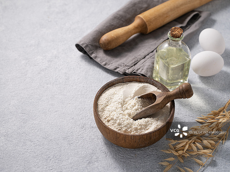 蓝色背景上的木碗燕麦粥，配有勺子、鸡蛋和擀面杖，天然有机面粉图片素材