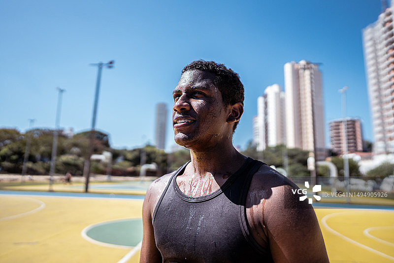 在运动场上沉思的快乐年轻人图片素材