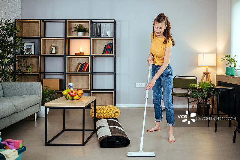 赤脚女人用湿拖把清洁地板图片素材