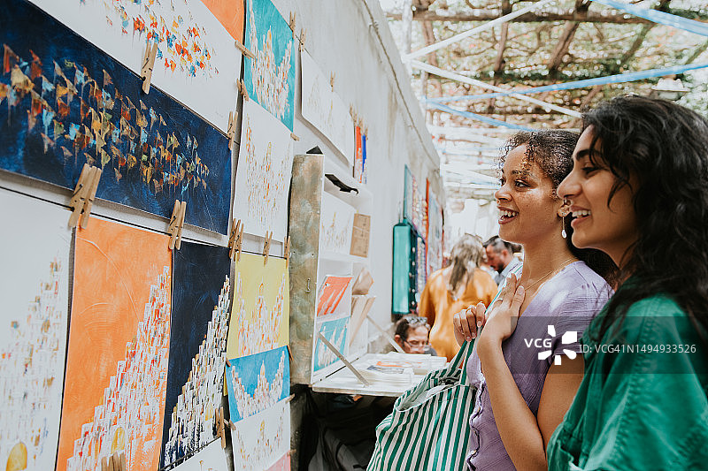 两位女人在户外市场摊位上欣赏艺术品图片素材