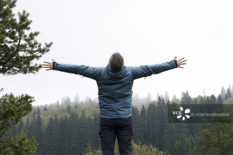 男人在森林前举起手臂图片素材