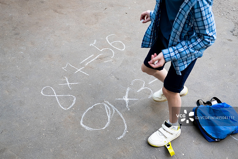 男孩在街上用粉笔写乘法例题图片素材