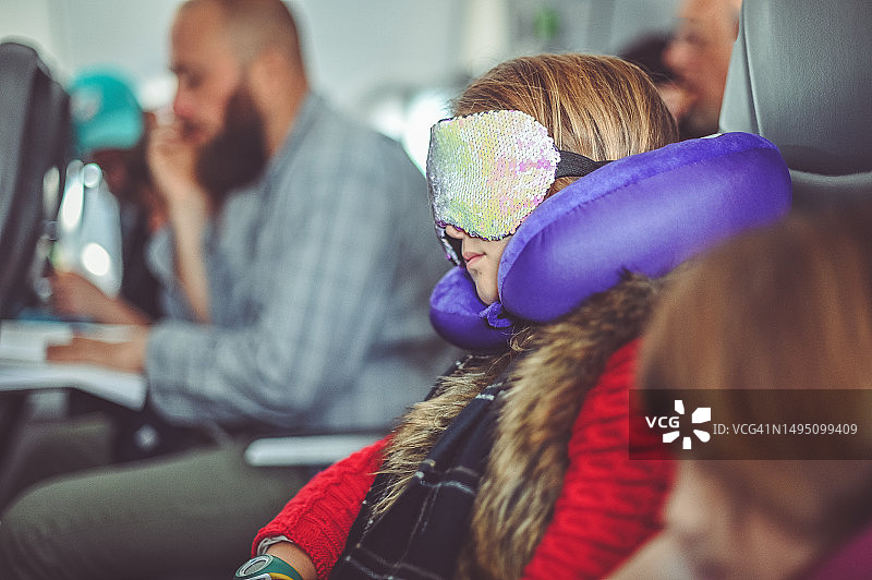 女孩在飞机上使用颈枕和眼罩睡觉图片素材