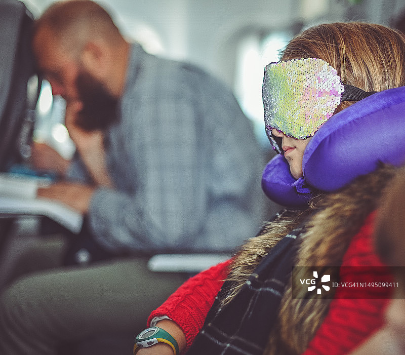 女孩在飞机上使用颈枕和眼罩睡觉图片素材