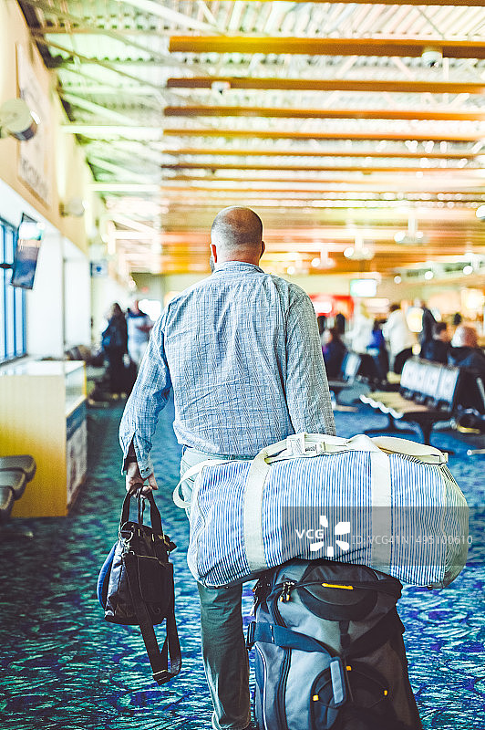 在机场拖着许多行李行走的男人（背影）图片素材
