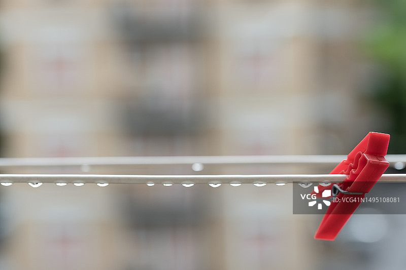 带雨滴的湿晾衣绳上的单个红色衣夹图片素材