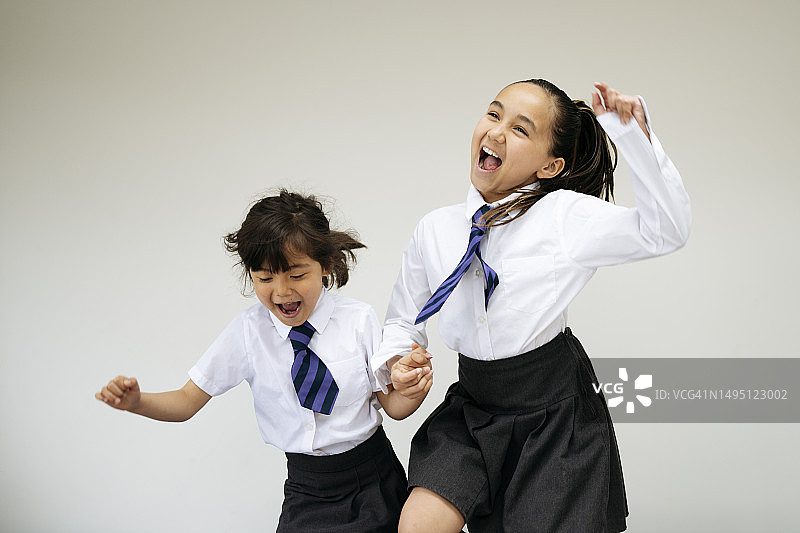 手牵着手跳跃的快乐姐妹图片素材