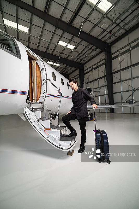 提着旅行包站在私人飞机台阶上的时尚男士图片素材