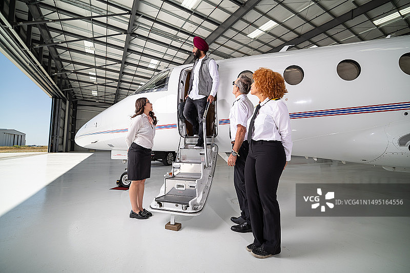 穿着灰色马甲站在私人飞机入口的男人图片素材