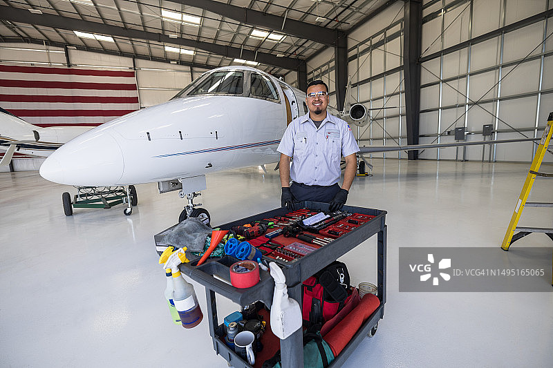 站在私人飞机前拿着工具微笑的技工图片素材