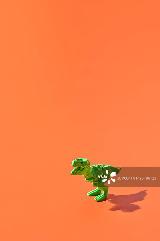 黄色背景上的绿色塑料霸王龙图片素材