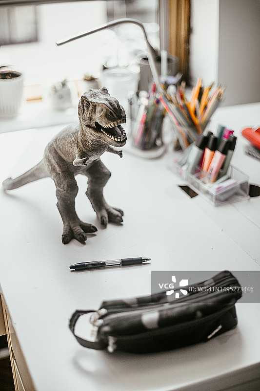 儿童书桌上的恐龙玩具和铅笔盒图片素材