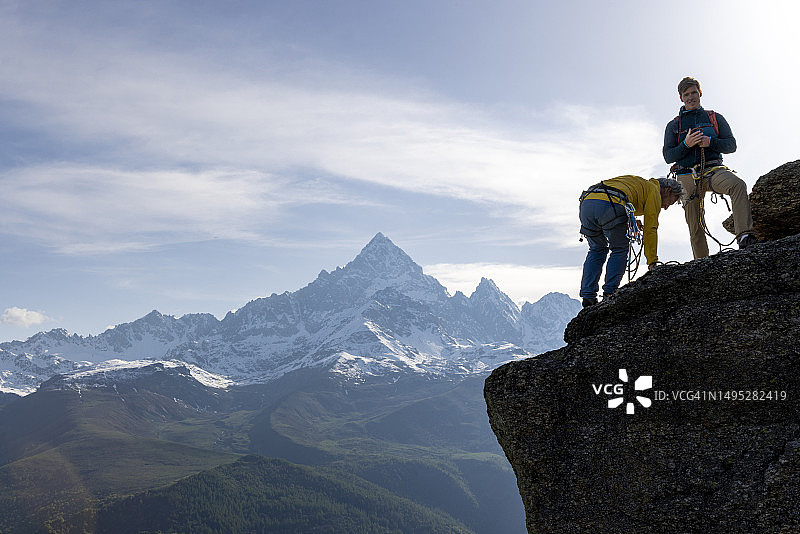 登山者准备从山顶扔绳索图片素材