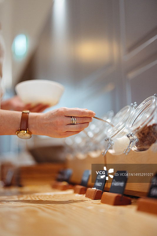 一位无法辨认的女子用勺子从碗里舀东西的手部特写图片素材