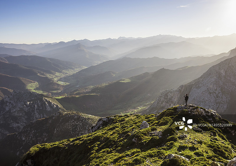 男子在西班牙坎塔布里亚的欧洲山峰徒步旅行，欣赏壮丽山景图片素材