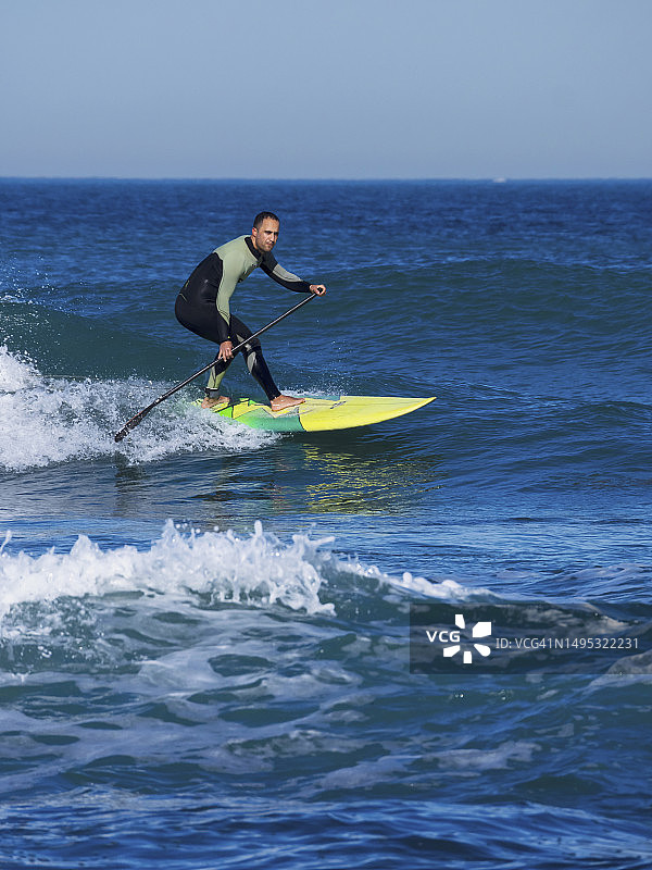 男子在索佩拉纳海滩用桨板冲浪图片素材