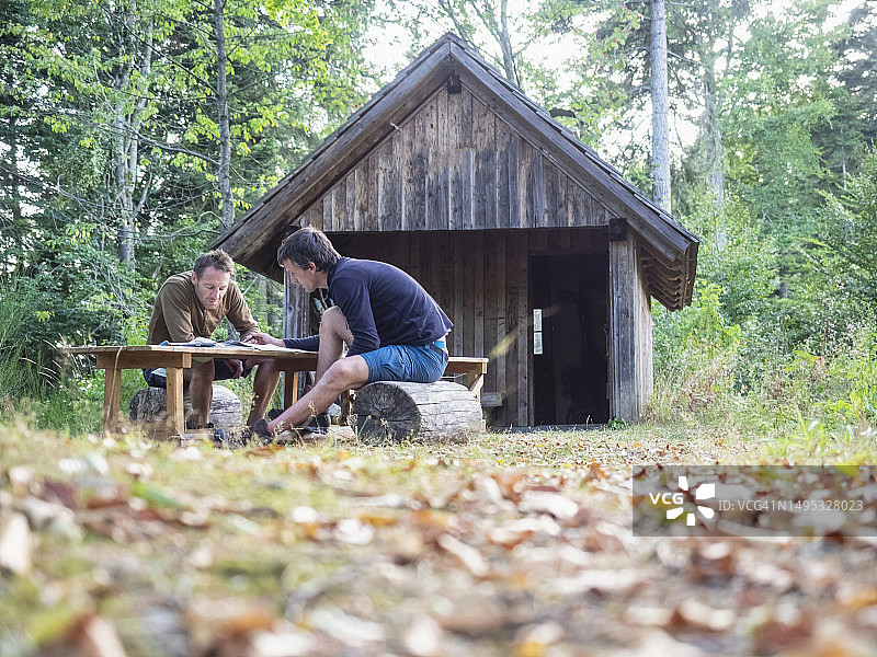 在德国巴登-符腾堡州黑森林，两名男子在小屋前阅读地图放松身心图片素材