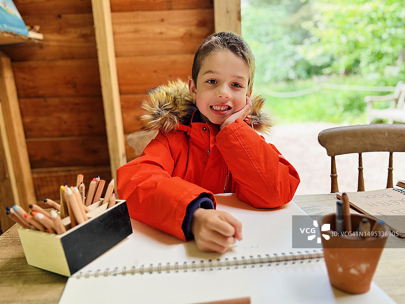 男孩坐着画画，看着镜头，很开朗图片素材
