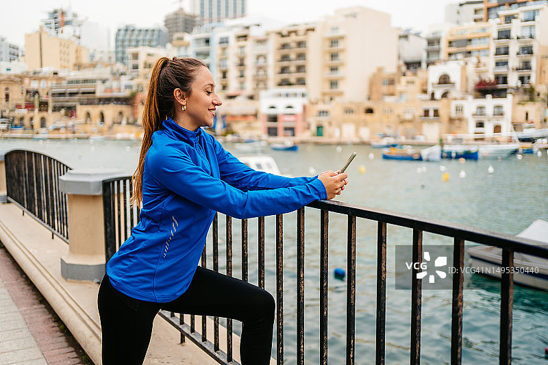 年轻女人在马耳他圣朱利安长廊锻炼后查看健身活动图片素材