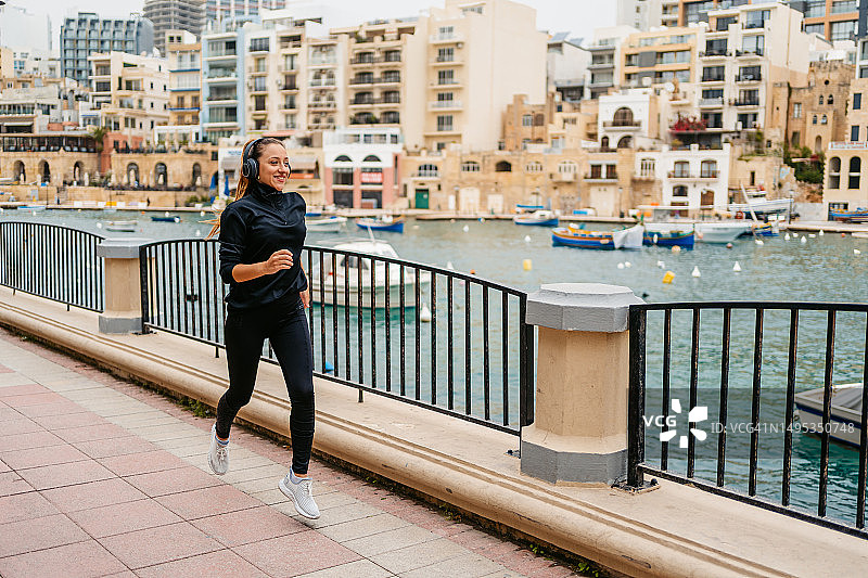 在马耳他圣朱利安长廊跑步时听音乐的年轻女人图片素材