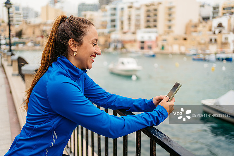 年轻女人在马耳他圣朱利安长廊锻炼后查看健身活动图片素材