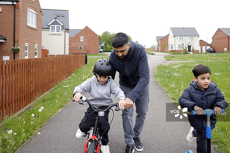 和爸爸一起学骑自行车的男孩图片素材