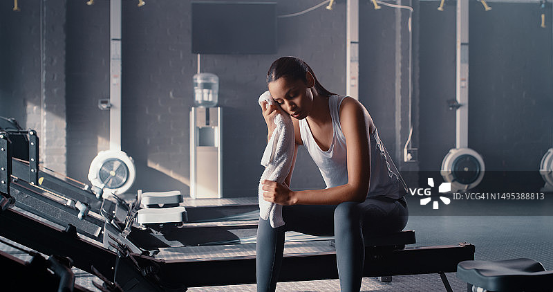 健身房里疲惫的女人拿着毛巾，用于擦汗、锻炼和休息图片素材