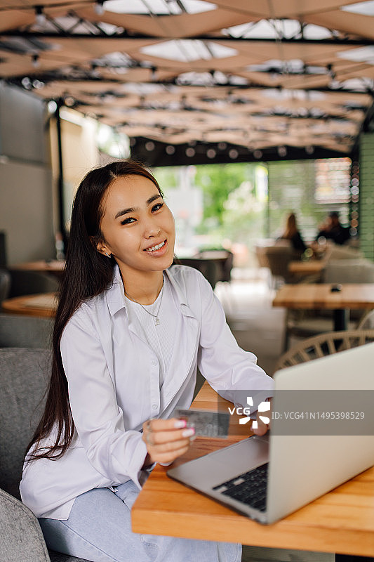 在街边咖啡馆规划行程的亚裔职业女性在线购买机票图片素材