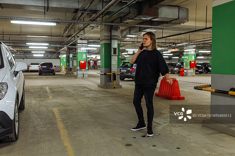 沮丧的年轻男子在地下车库空旷的停车场打电话给警察图片素材