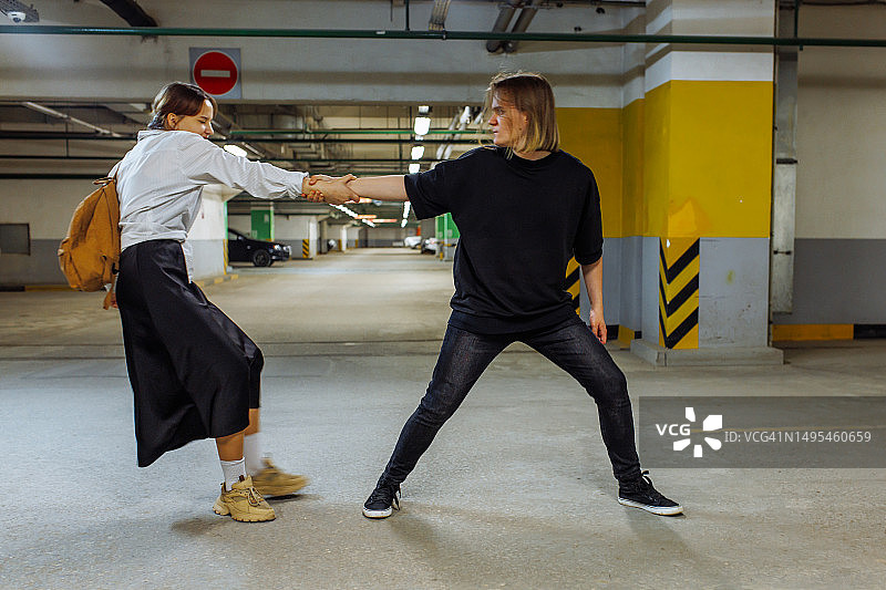 地下停车场，年轻男子拉着女友的手激烈争吵图片素材