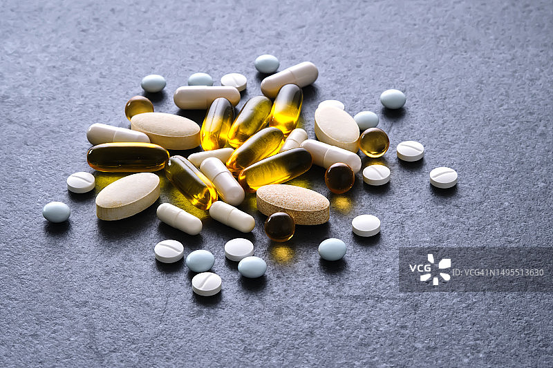 深色桌子上的药片、维生素和膳食补充剂图片素材