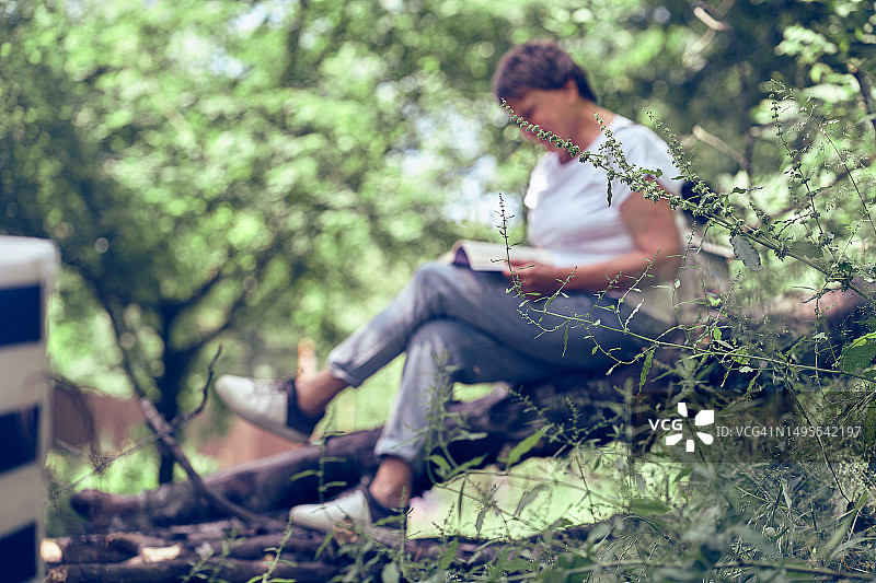在森林里读书的背包中年妇女，留白图片素材