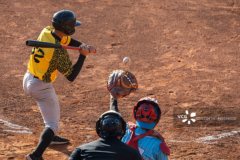 棒球比赛中击球手挥棒落空，捕手和裁判关注球的瞬间图片素材