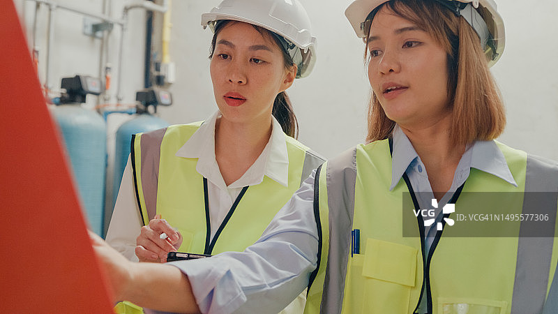 戴着安全帽的年轻亚洲女工业工程师在化工厂检查蒸汽锅炉，重工业和工程师团队图片素材