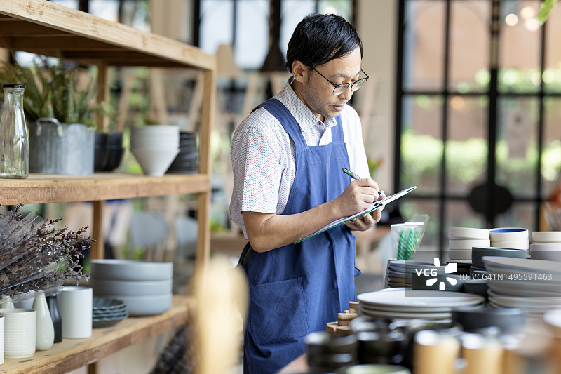 提高货架商品可见性，减少损失并在缺货前补货。一位日本店主在零售展示区检查厨房产品的可用性和补货情况。图片素材