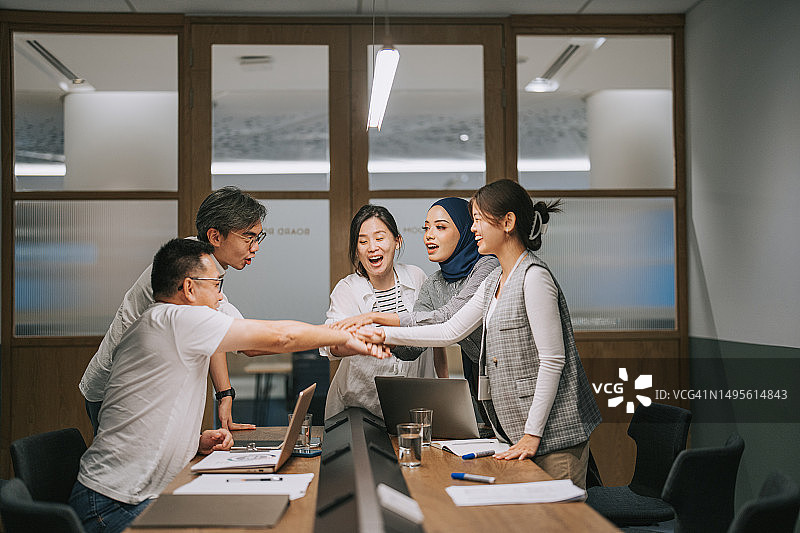 多元文化亚洲同事在会议室携手合作图片素材