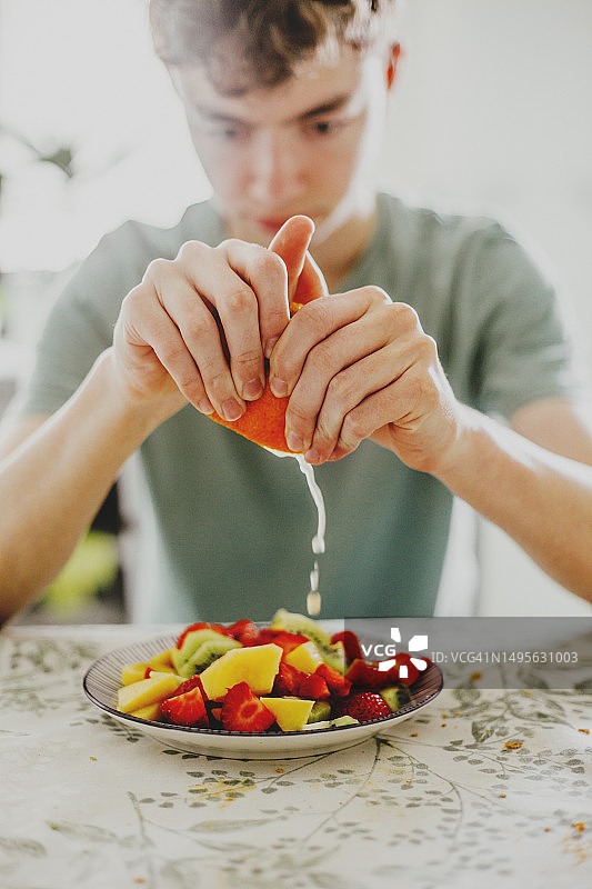 男人将橙子汁挤到水果沙拉上图片素材