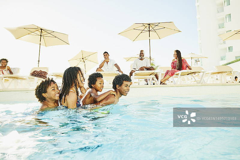 在热带度假村游泳池里玩耍的微笑的兄弟姐妹图片素材