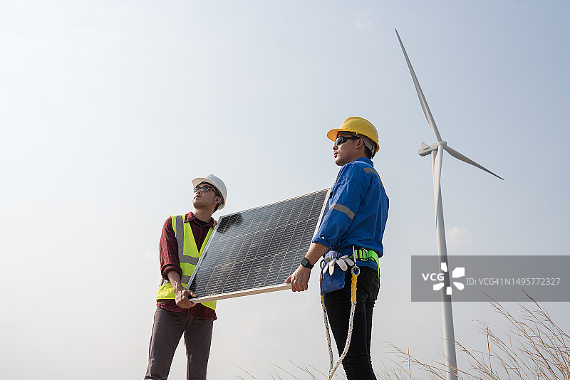 工程师在风力涡轮机旁吊装太阳能电池板图片素材