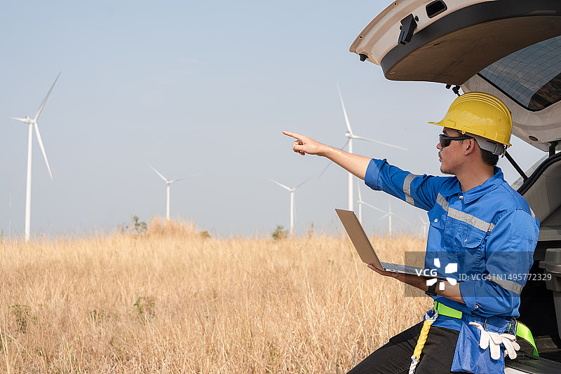 亚洲工程师在汽车内使用笔记本电脑检查风力涡轮机的工作系统图片素材