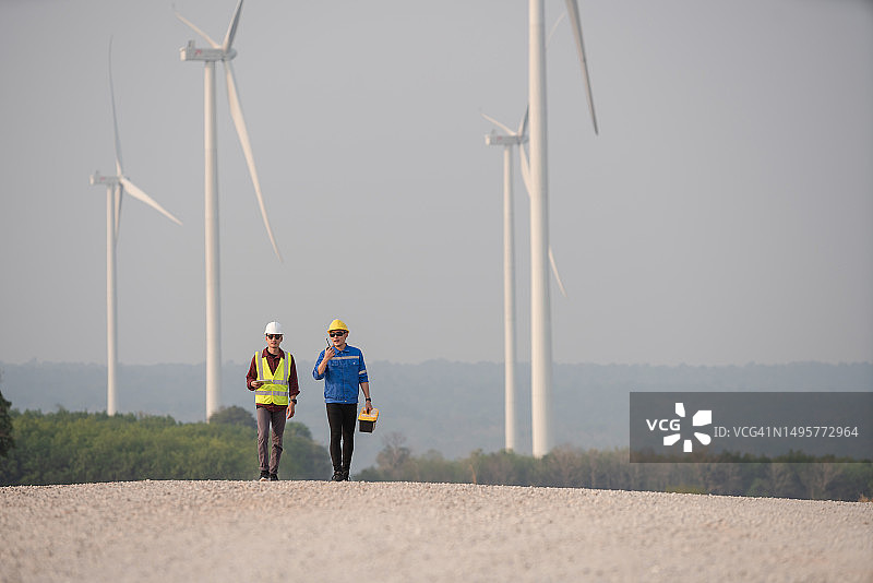广角镜头：工程师与技术员检查风力涡轮机可再生能源图片素材
