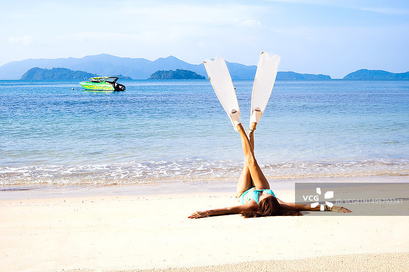 身穿比基尼的女人在热带海滩上戴着浮潜鳍图片素材