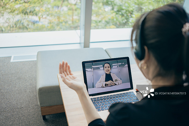 正在使用笔记本电脑和耳麦进行视频通话的亚洲女商人图片素材